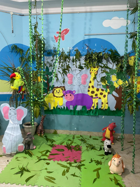 A vibrant jungle-themed bulletin board featuring colorful animal cutouts, lush green trees, and jungle plants, with a “Welcome to the Jungle” sign at the center.