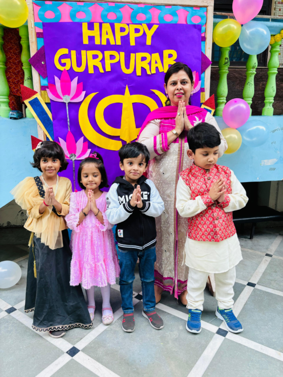 A joyful GurPurab celebration at Udayan Kidz Premium Preschool and Day Care Center, featuring a decorated background board themed for the occasion with a teacher and group of students standing in front.