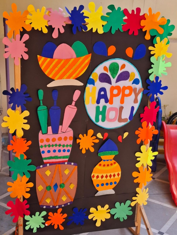 Bright and colorful Holi-themed bulletin board with festive decorations, traditional pots, pichkaris, and vibrant splashes of color.