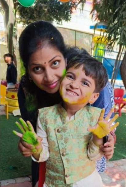 Preschool Holi celebration with colorful handprint banner and happy children.